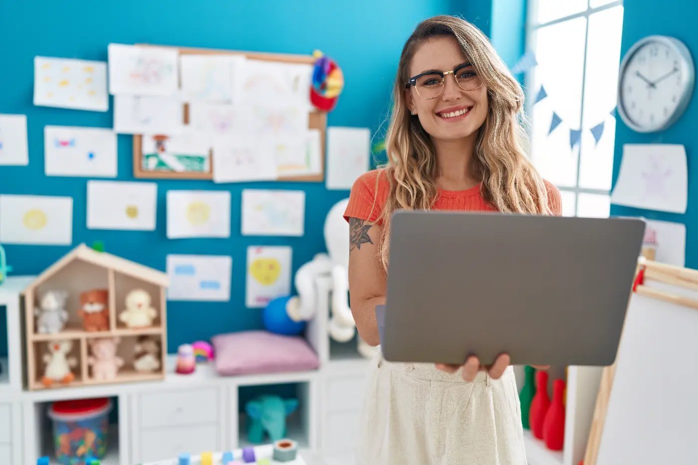 Female teacher holding her laptop in a classroom